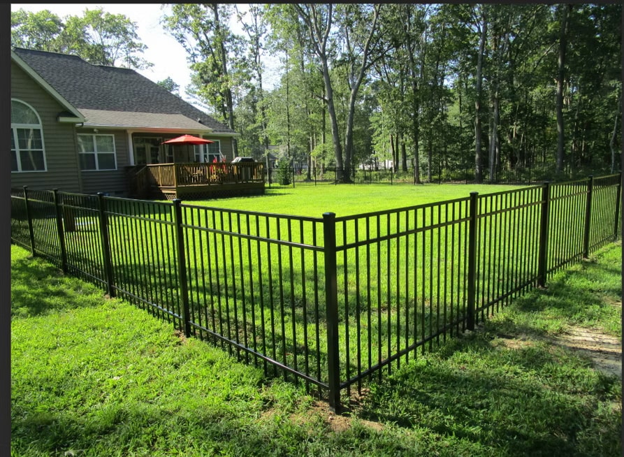Black metal fence surrounding green lawn